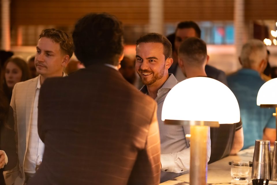 Two members smiling in conversation at the bar beside glowing table lamps
