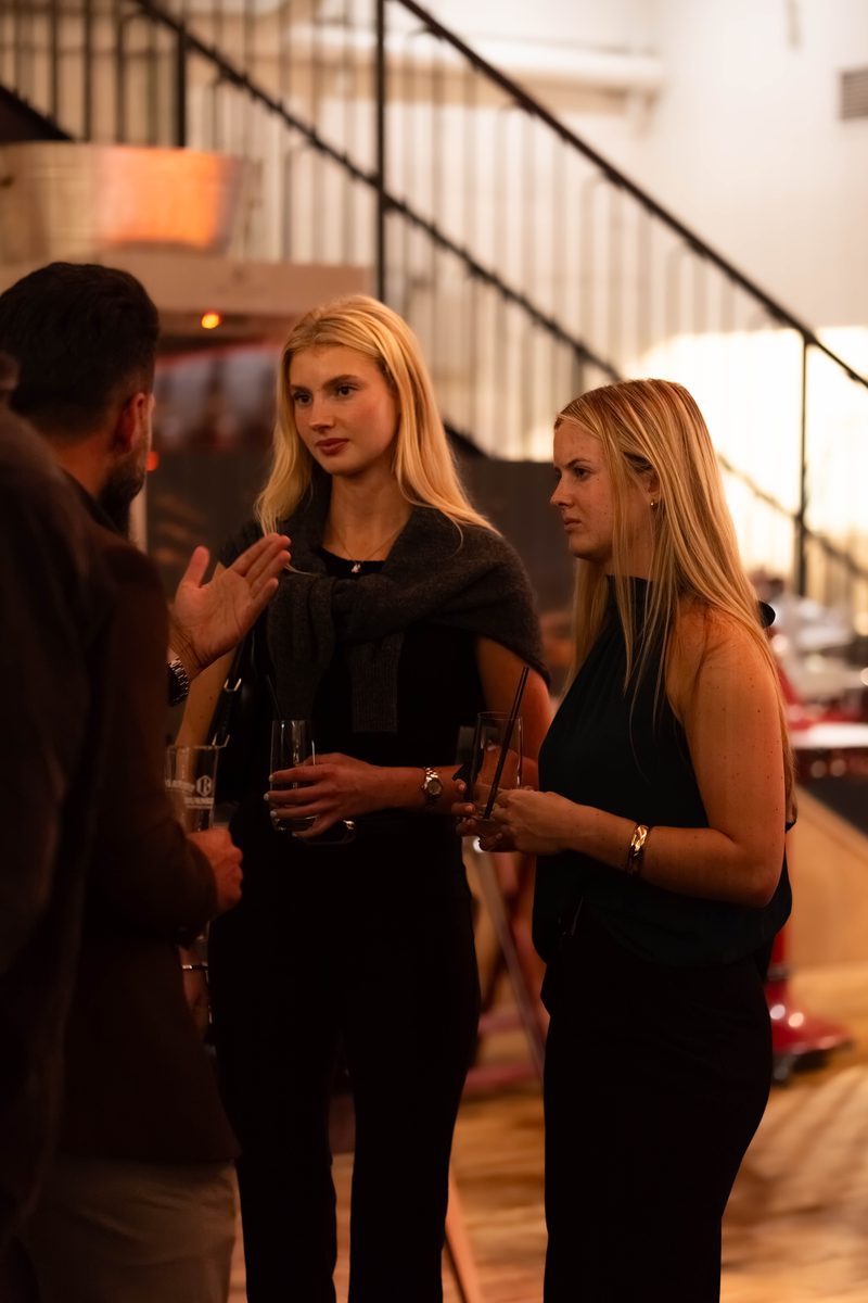 Two members talking with drinks beside the staircase