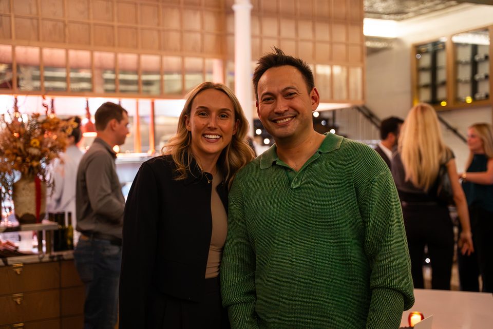 Two members smiling for a photo at the bar, with the room behind them
