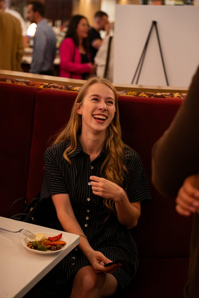 A member laughing in the red booth, with a plate of appetizers on the table